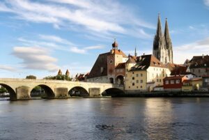 The Stone Bridge and Regensburg Cathedral spires overlooking the Danube River in Regensburg, Germany.