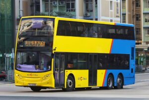 Yellow and blue Citybus double-decker bus driving on a Hong Kong city street in front of residential buildings.