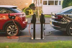 Two electric vehicles charging at Connected Kerb bollards on a residential street.