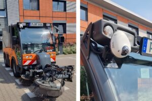 A Cortexia AI camera mounted to the roof of an orange street sweeper vehicle parked in front of a brick building.