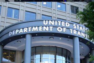 Exterior signage for the United States Department of Transportation on a curved building entrance with grey columns.