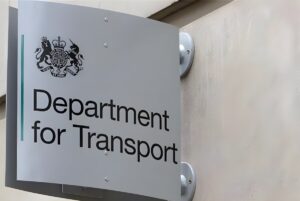 A Department for Transport sign featuring the UK Royal Coat of Arms mounted on a stone building exterior.
