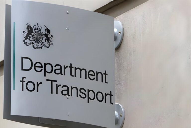 A Department for Transport sign featuring the UK Royal Coat of Arms mounted on a stone building exterior.