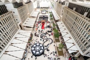 High-angle view of people walking through the Barahat Msheireb courtyard with retractable white awnings in Doha, Qatar.