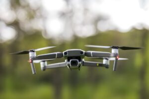 DJI Mavic 2 Pro quadcopter drone hovering in mid-air against a blurred green forest background.