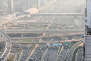 Aerial view of a multi-level highway interchange in Dubai featuring the RTA metro line and station.