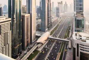 Aerial view of Sheikh Zayed Road in Dubai featuring heavy traffic, skyscrapers, and a Dubai Metro station.