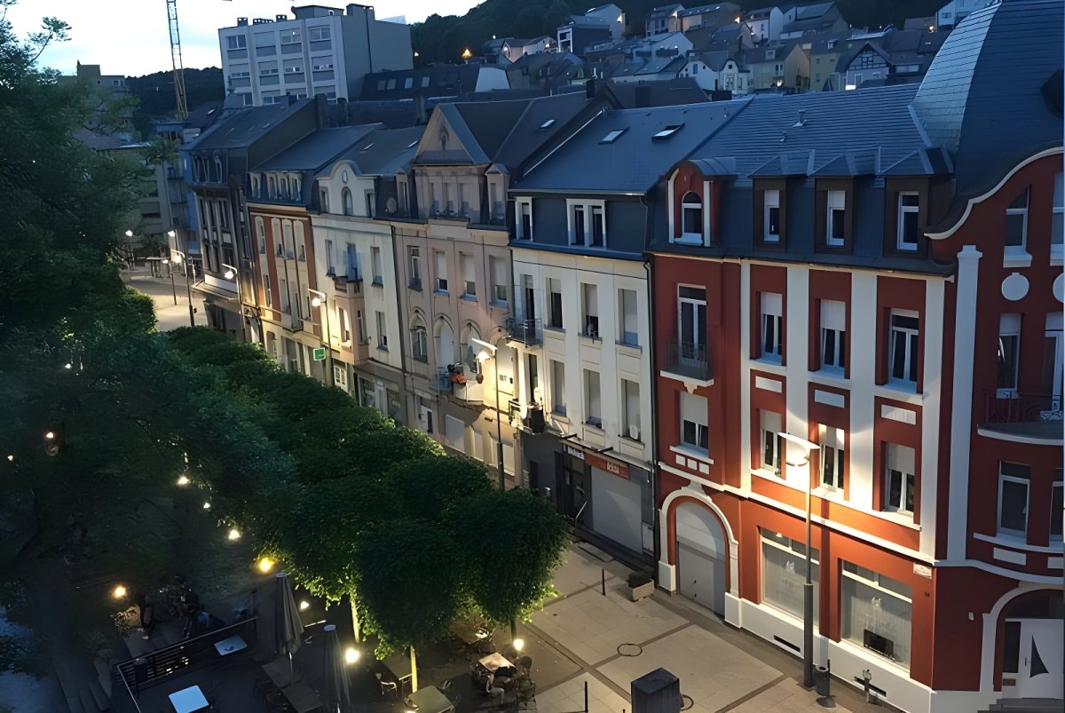 Elevated view of a Differdange street at dusk with illuminated LED street lights and historic multi-story buildings.