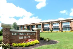 Brick monument sign for Eastside Utility District in front of a two-story brick office building on a grassy hill.