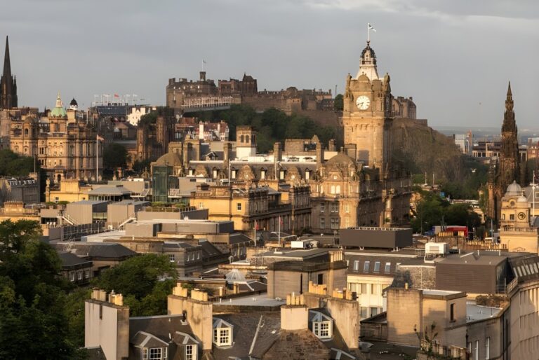 Elevated view of the Edinburgh skyline featuring the Balmoral Hotel clock tower and Edinburgh Castle on a hill.