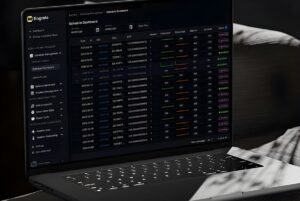 Laptop displaying the Engrate digital dashboard with data tables for energy and grid integration management.