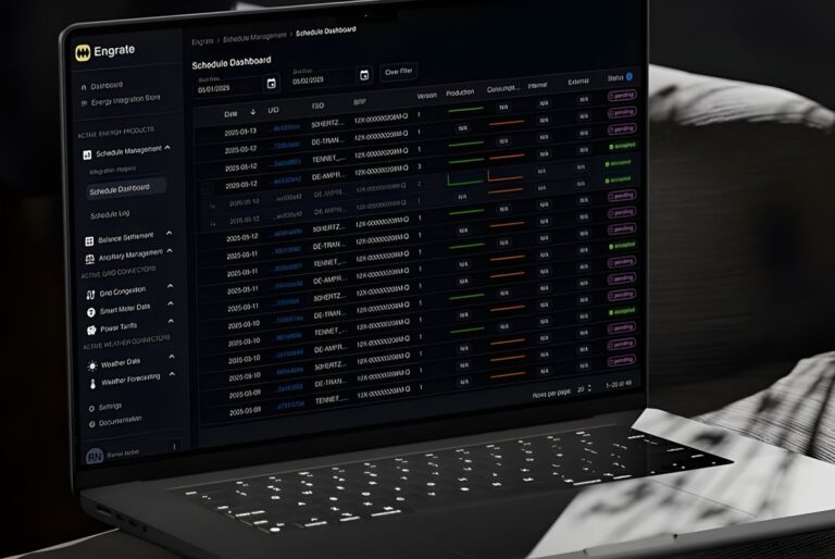 Laptop displaying the Engrate digital dashboard with data tables for energy and grid integration management.