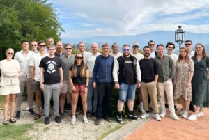 The Enode team stands together outdoors on a gravel path with mountains and a blue sky in the background.