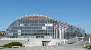 European Investment Bank headquarters in Luxembourg featuring a curved glass facade and international flags.