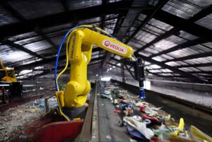 Yellow EverestLabs robotic arm with Veolia branding sorting waste on a conveyor belt inside a recycling facility.