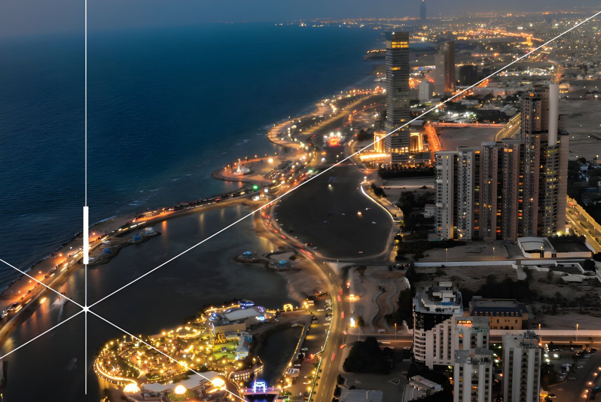 Aerial night view of the Jeddah Corniche coastline featuring illuminated streets, skyscrapers, and a digital star graphic.