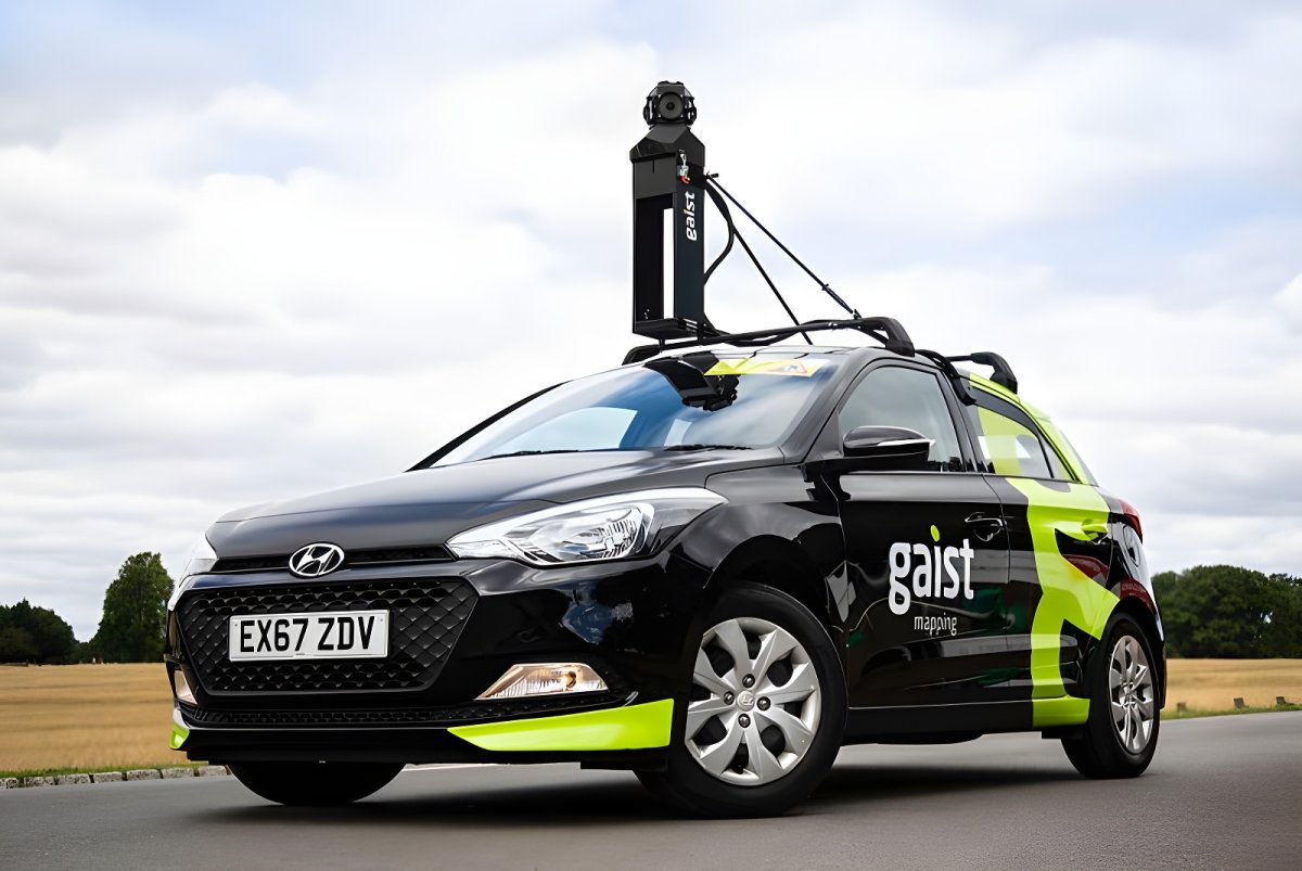 A Gaist branded mobile mapping vehicle with a roof-mounted 360-degree camera system parked on a rural road.