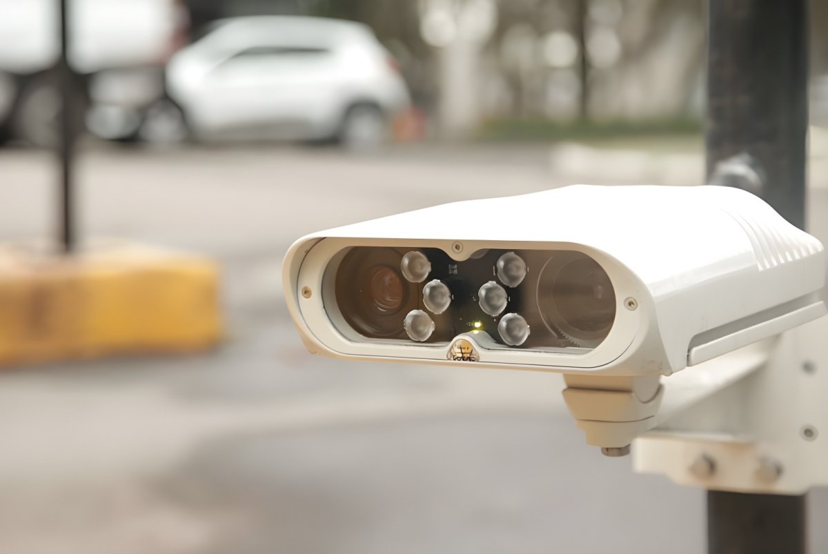 Genetec AutoVu SharpV automatic license plate recognition camera mounted on a pole in a parking lot.