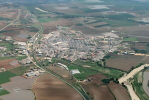 Aerial view of a small town in the Gran Vega region of Andalusia surrounded by agricultural fields and a winding river.