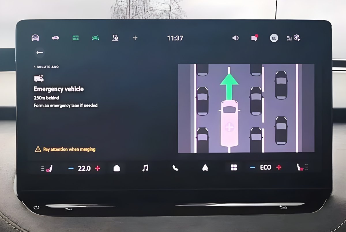 Vehicle infotainment screen displaying a digital safety alert for an approaching emergency vehicle in traffic.