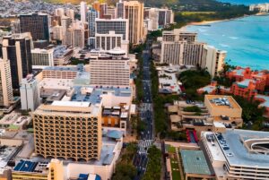 Aerial view of high-rise buildings and traffic on Kalakaua Avenue along the Waikiki coastline in Honolulu, Hawaii.