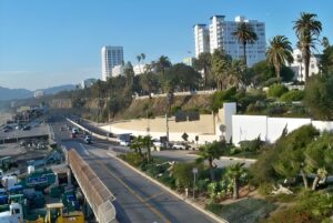High-angle view of traffic on the Pacific Coast Highway in Santa Monica with palm trees and coastal buildings.