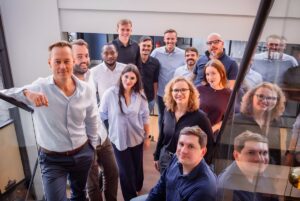 A group of Hulo team members standing together on an indoor staircase in an office setting.
