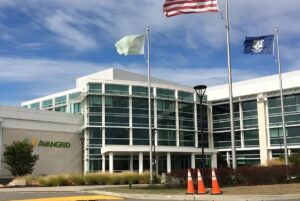 Avangrid corporate office building with glass facade, company signage, and flags flying under a blue sky.