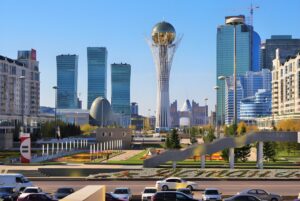 The Baiterek Tower and modern skyscrapers in the Astana city center skyline under a clear blue sky.