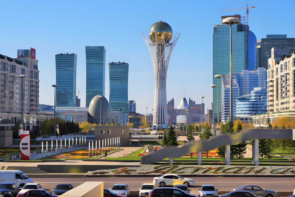 The Baiterek Tower and modern skyscrapers in the Astana city center skyline under a clear blue sky.