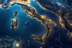 Satellite view of Italy at night with glowing city lights illuminating the coastline and urban centers.