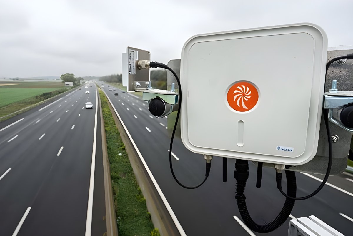 LACROIX traffic management sensor and camera mounted on a bridge overlooking a multi-lane highway with moving vehicles.