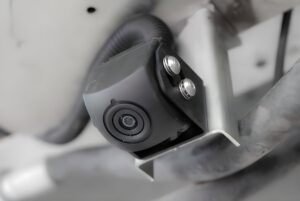 Close-up of a black Lixo computer vision camera mounted on a metal bracket of a waste collection vehicle.