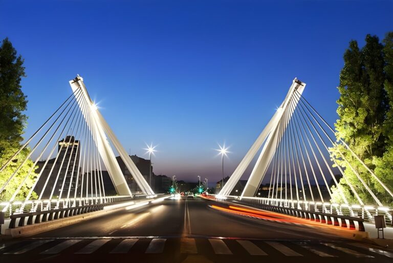 Illuminated cable-stayed bridge in Lleida at dusk with light trails from passing vehicles.