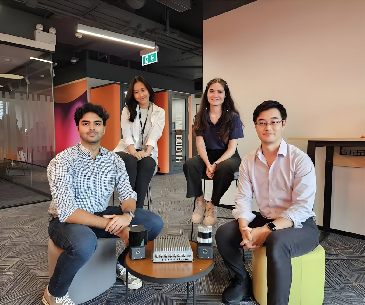 Four Kodifly team members pose in a modern office with LiDAR sensors and hardware displayed on a central coffee table.