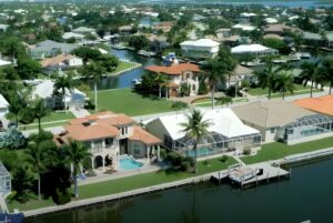 Aerial view of waterfront residential homes with private docks and palm trees along a canal in Marco Island, Florida.