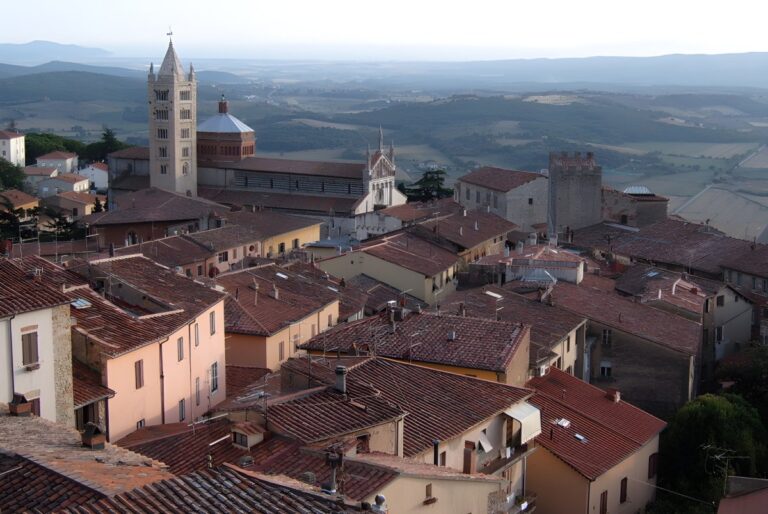 High-angle view of the historic Massa Marittima skyline featuring the Cathedral of Saint Cerbonius and terracotta rooftops.