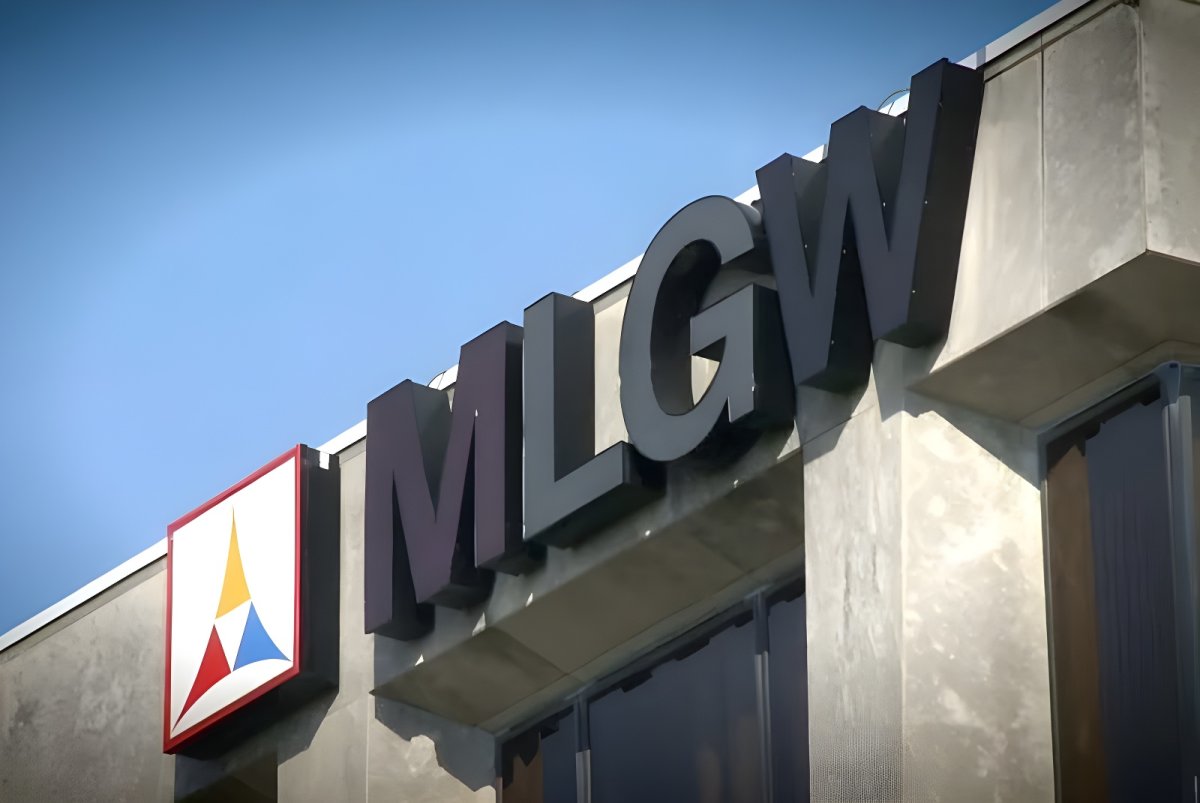 Low-angle view of the MLGW logo and signage on the exterior of a concrete utility building under a clear blue sky.
