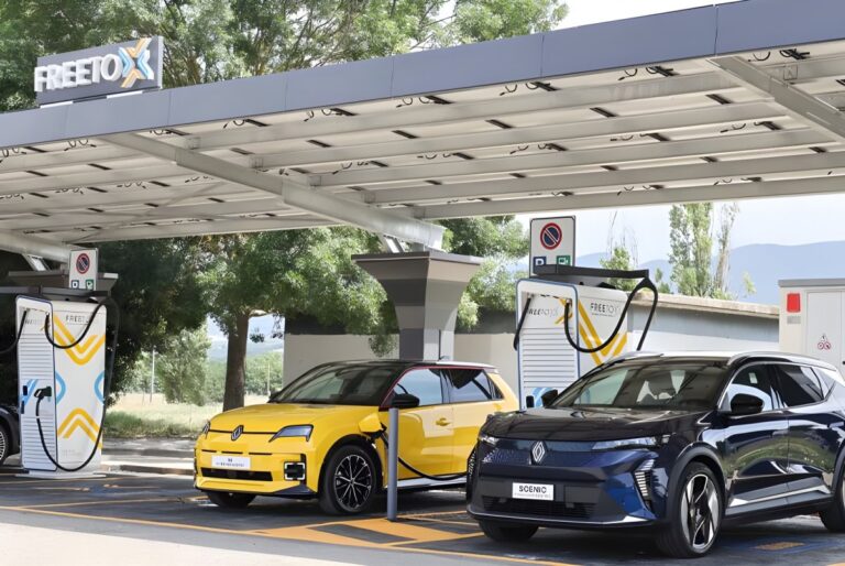 Renault electric vehicles charging at a Free To X station under a solar panel canopy at an Autostrade per l'Italia site.