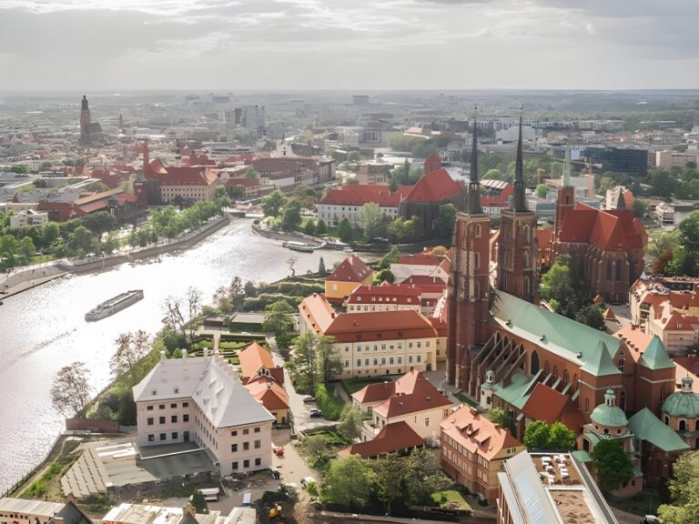 Aerial view of Wrocław, Poland, featuring the Odra River and the Gothic spires of the Cathedral of St. John the Baptist.