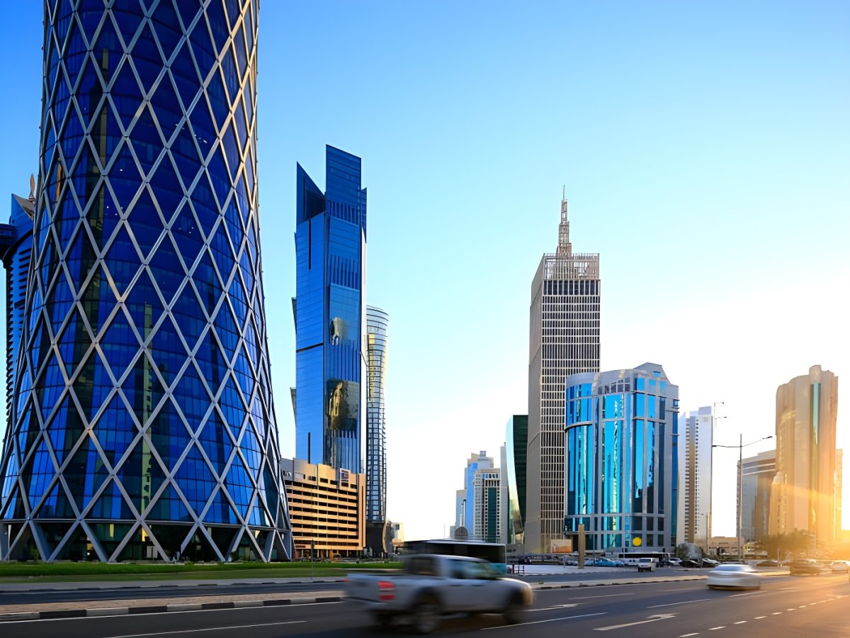 Modern skyscrapers including the Burj Doha and Al Bidda Tower line a multi-lane highway in the West Bay district of Doha.