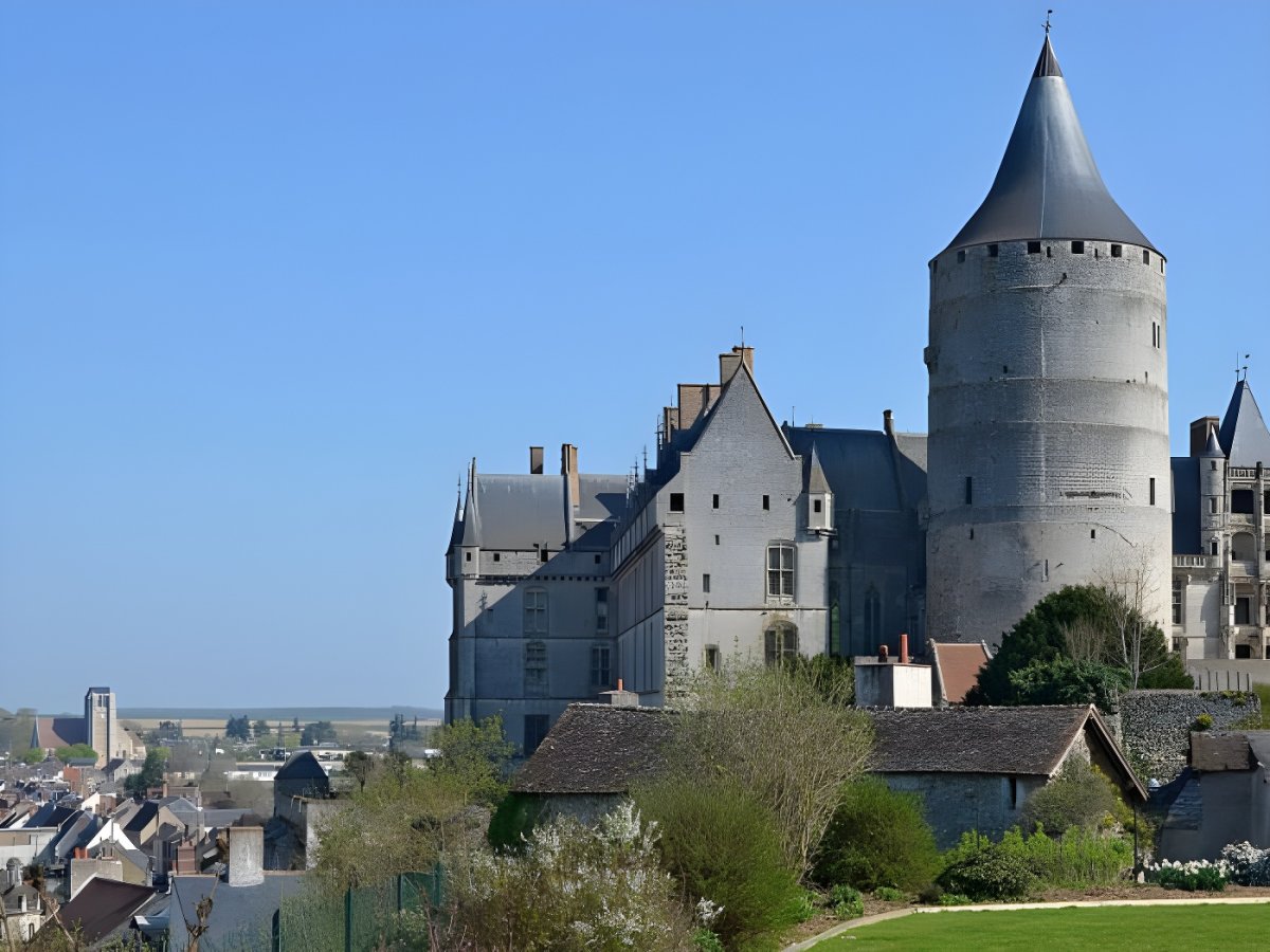 The medieval Château de Châteaudun featuring a large stone keep and gothic wing overlooking the town under a clear blue sky.