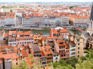 High-angle view of Lyon, France, featuring orange-roofed buildings along the Saône river and the Passerelle Saint-Georges.