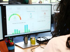A person views a digital dashboard on a computer monitor displaying water consumption charts and utility data analytics.