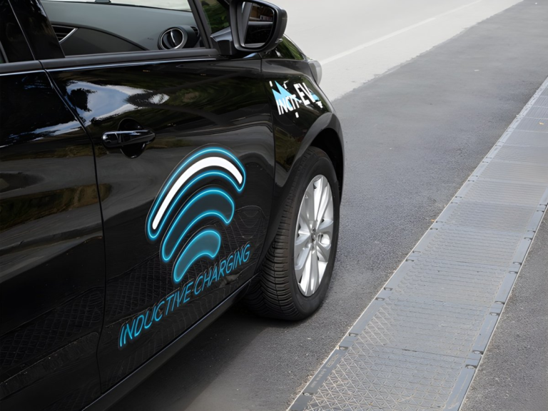 Black electric car with inductive charging decals parked next to an embedded wireless charging track in the asphalt.