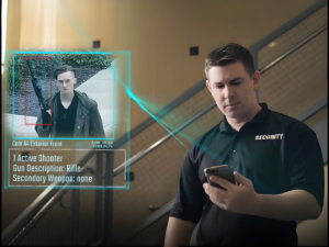 Security guard viewing a ZeroEyes digital alert on a smartphone showing a detected rifle in a surveillance feed.