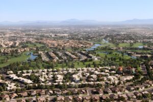 Aerial view of a residential suburban development in Chandler, Arizona, featuring houses, green spaces, and water canals.