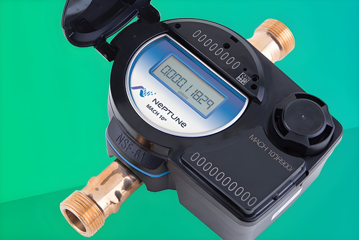 Close-up of a Neptune Mach 10 ultrasonic smart water meter with a digital display and brass pipe fittings.