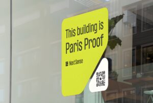 A Next Sense "Paris Proof" decal with a QR code on a glass window reflecting an office interior.