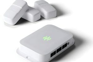Nrlyze smart building gateway with a glowing green logo and three wireless sensors on a white background.